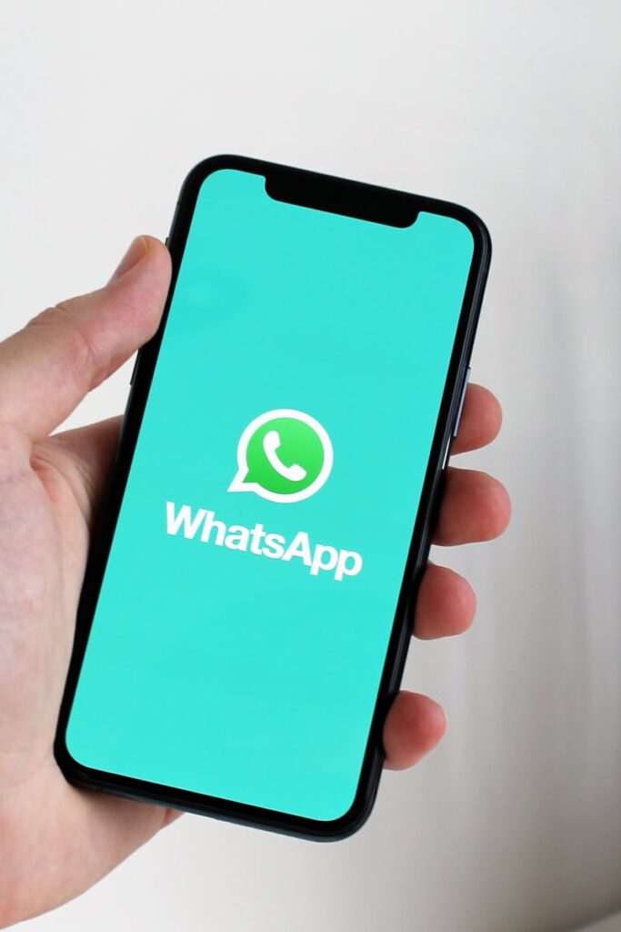 Close-up of a hand holding a smartphone displaying the WhatsApp app screen.